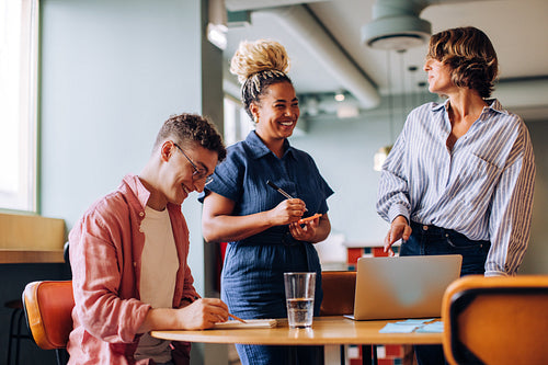Three colleagues discussing ideas together at their workplace in an office setting