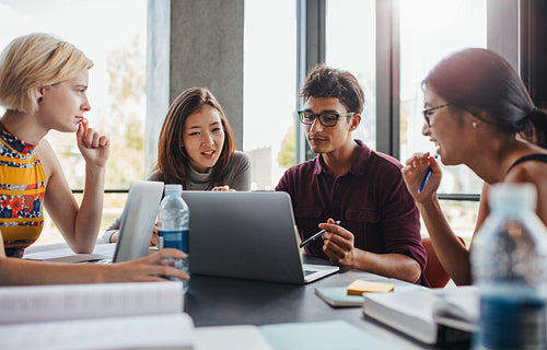 Multiracial young people doing group study at library