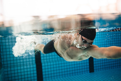 Pro male swimmer in action inside swimming pool