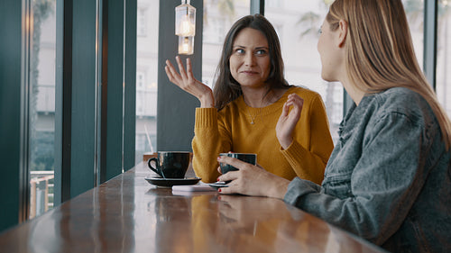 Two female friends talking at a coffee shop