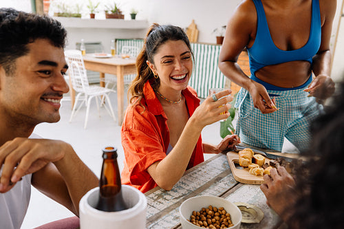 Friends laughing together while sharing snacks at a cozy table gathering