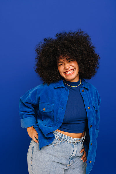 Excited young woman smiling at the camera against a blue background