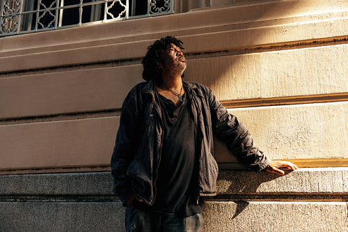 Middle aged homeless man looking up thoughtfully outdoors