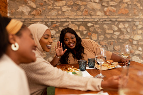 Happy female friends having a video call in a restaurant