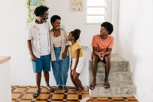 Playful young girl landing from a jump, enjoying family time with her parents and brother at home