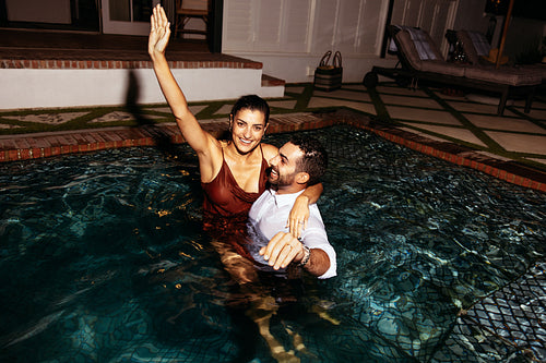 Cheerful young couple swimming in their clothes at night