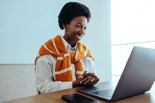 Professional black businesswoman sitting at a desk with laptop during an online meeting