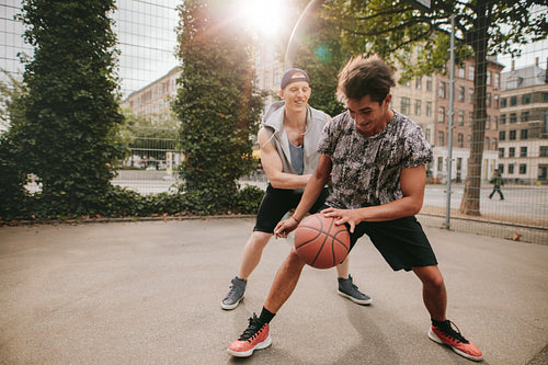 Friends playing basketball on court and having fun