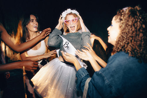 Friends celebrating with a joyful woman wearing a costume and party accessories