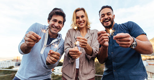Group of friends enjoying rooftop party with sparklers