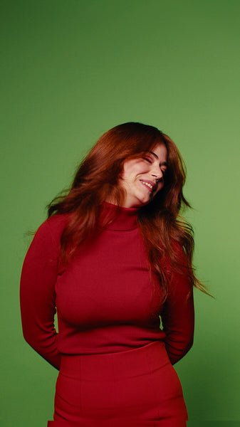 Happy young woman in red with green screen background shaking her hair