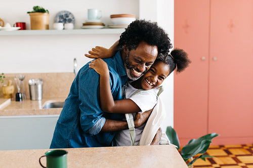 Morning routine: Father and daughter embracing in the kitchen at home