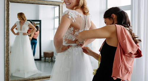 Designer fitting bridal gown to future bride