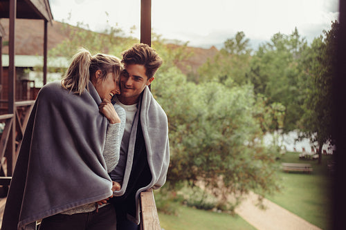 Holiday couple in hotel balcony wrapped in blanket