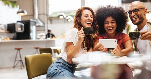 Three cheerful friends doing a video call while on a coffee date