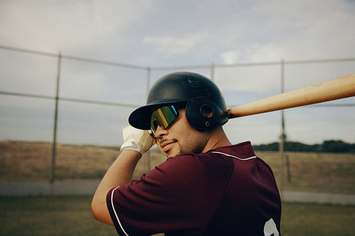 Male baseball player ready to swing bat at ballpark during practice session on a sunny day