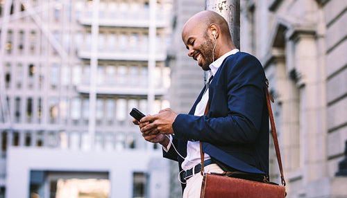 African businessman walking outdoors with mobile phone