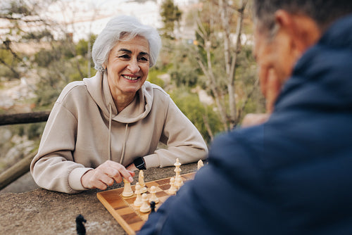 Carefree senior couple playing chess together outdoors