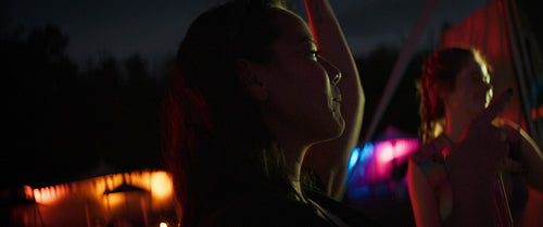 Diverse group of young adults dancing and cheering at a music festival at night