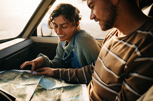 Young couple maps out journey inside a car