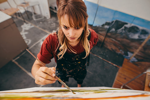 Young female artist painting picture in studio