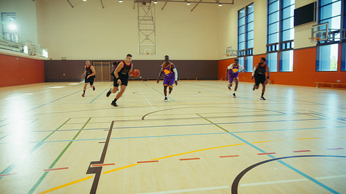 Young men playing basketball in gym