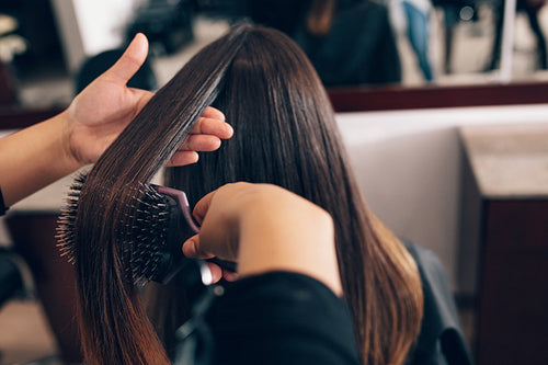Female hair stylist working on a woman 's hair at salon