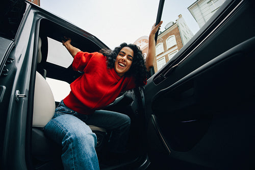 With a cheerful smile, the woman exits her car on the city street