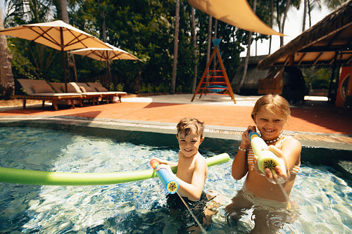 Summer splash: Children playing joyfully with water toys in a pool