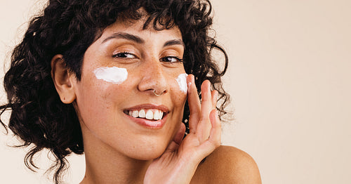 Ethnic woman moisturizing her face