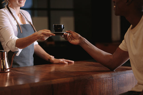 Female barista serving customer inside a coffee shop