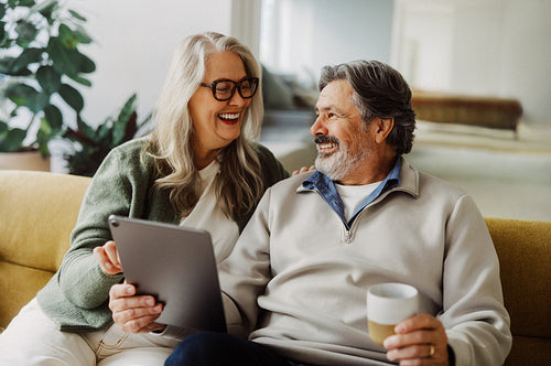 Senior couple browse online content on a tablet at home