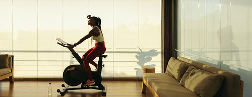 Fitness and wellbeing: African woman using exercise bike for healthy lifestyle