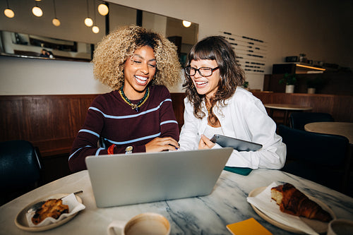 Women friends working on a laptop and laughing