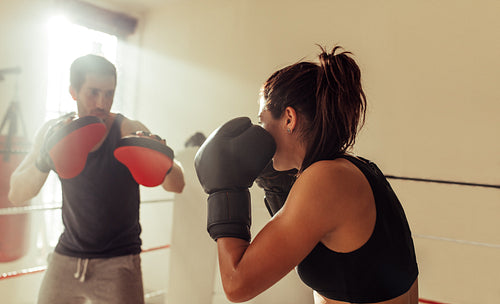 Female boxer training with a coach in a gym