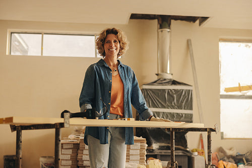 Happy homeowner smiles while renovating kitchen interior with wood panel upgrades and baseboards