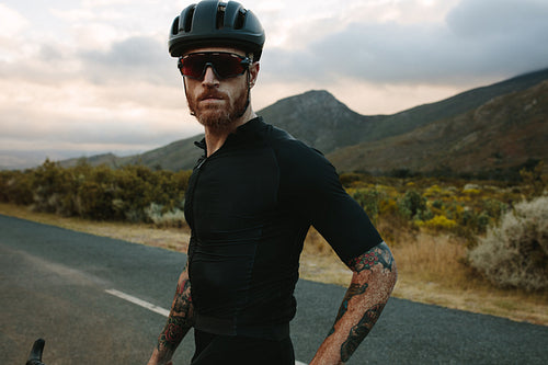 Cyclist with bicycle standing outdoors