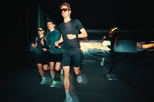 Running club training together outdoors in an urban tunnel with motion blur