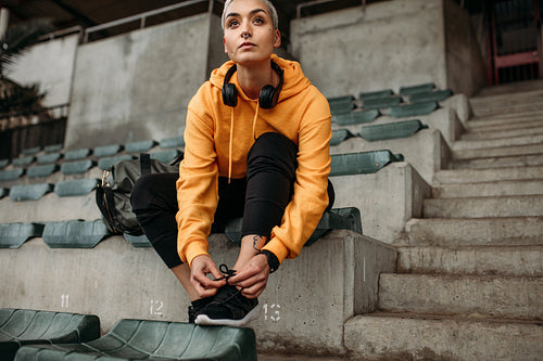 Athlete sitting in stands of a stadium tying shoelace
