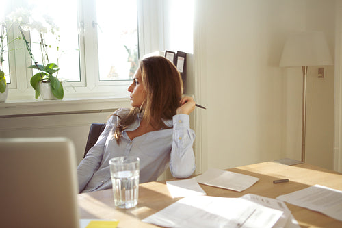 Business woman in home office looking away thinking