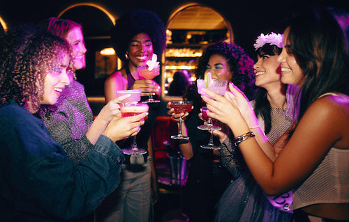 Group of friends celebrating with cocktails during a festive night out