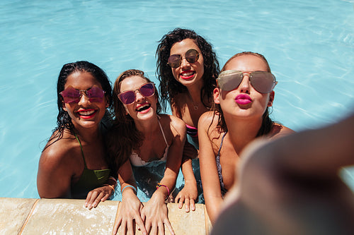 Girls posing for group selfie in pool