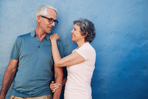 Romantic couple standing together against a blue wall