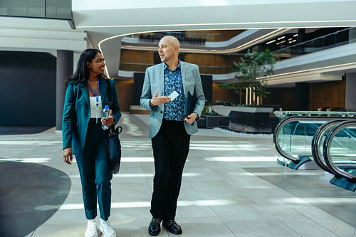 Corporate colleagues walking and discussing in modern office building