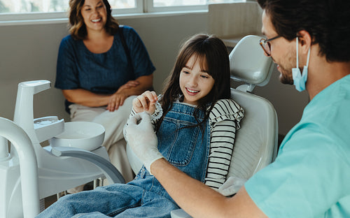 Young girl receives dental aligners during clinic visit with her mother