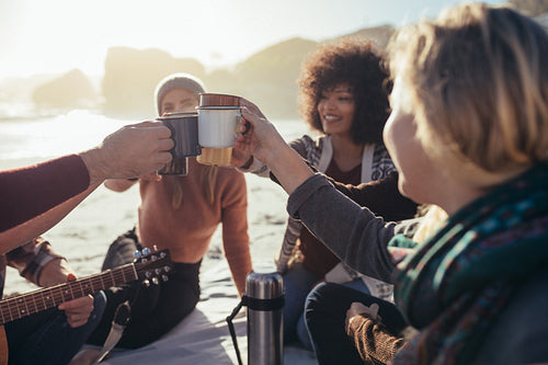 Friends cheering coffee at beach