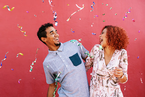 Happy young couple celebrating with confetti in air.