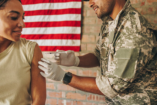 Army medic injecting a female soldier with the covid-19 vaccine