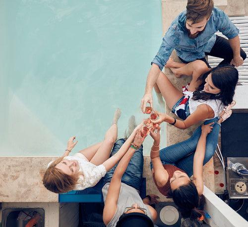 Group of friends toasting at poolside party