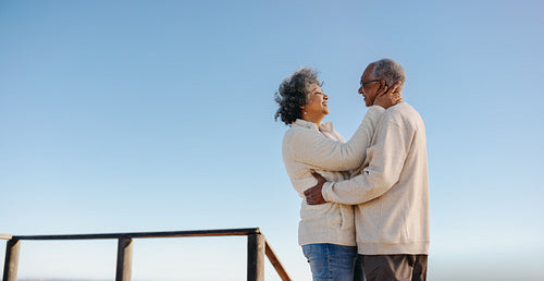 Happy senior couple smiling at each other on a foot bridge